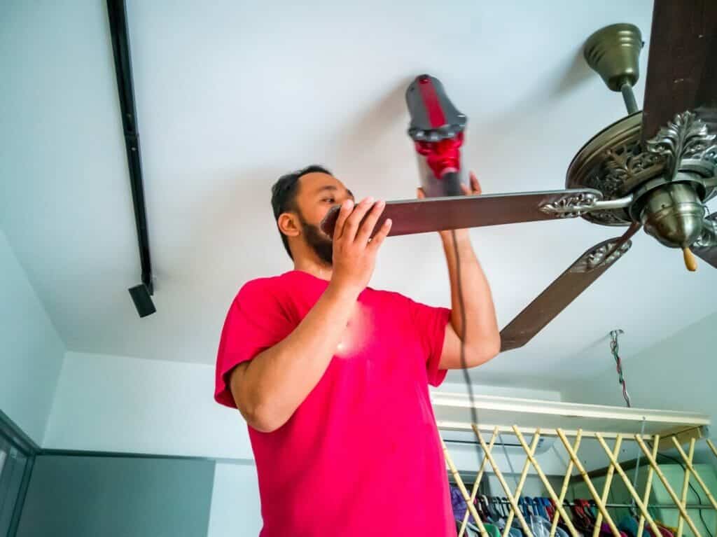bearden man is vacuuming the ceiling fan. house cleaning, spring cleaning