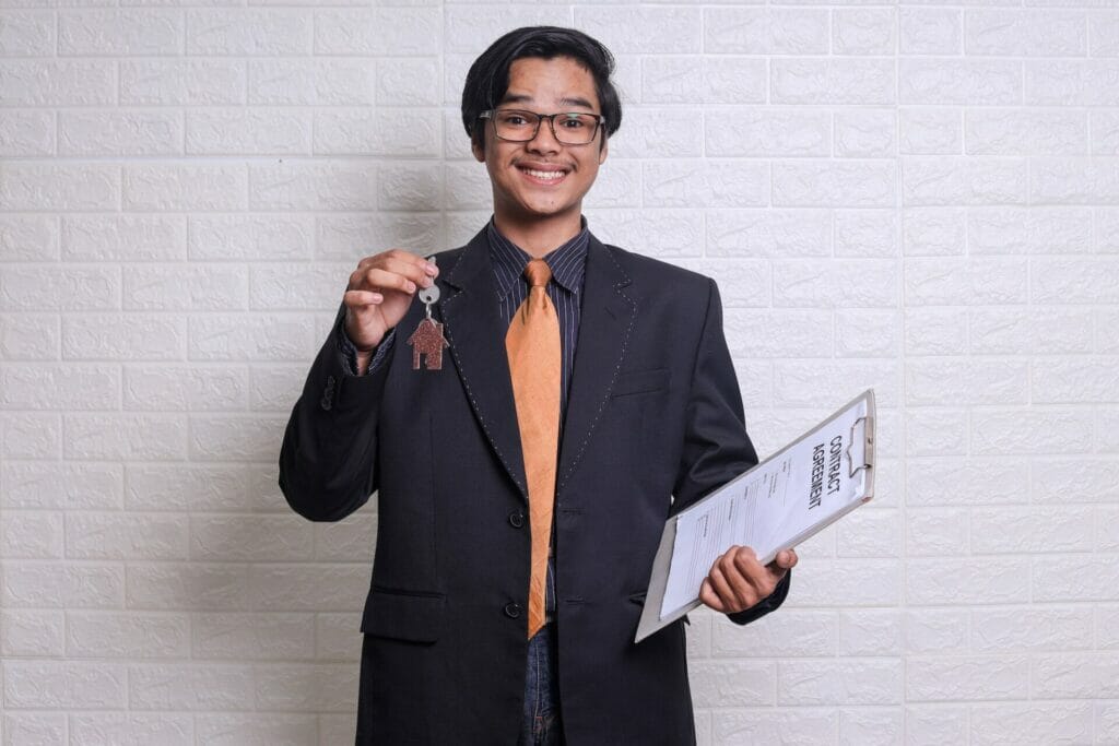 Property agent holds home key and document for housing finance.